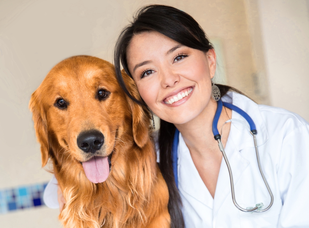 A vet smiles joyfully next to a happy dog